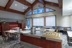 un restaurante con mesas, sillas y ventanas grandes en Residence Inn by Marriott Charleston Airport, en Charleston