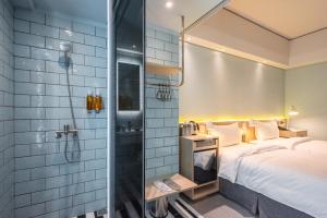 a bathroom with a shower and a bed in a room at Ramble Hotel in Taichung