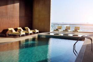 a hotel room with a swimming pool with chairs at Marriott Executive Apartments Downtown, Abu Dhabi in Abu Dhabi