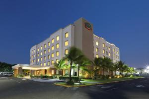 a large building with palm trees in front of it at Courtyard by Marriott Panama Metromall in Tocumen