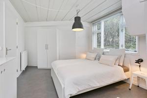 een witte slaapkamer met een wit bed en een raam bij Zeeuwse Kustbunker in Groede