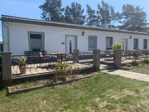 a white building with picnic tables and a fence at Ferienpark Buntspecht Apartment A in Pruchten
