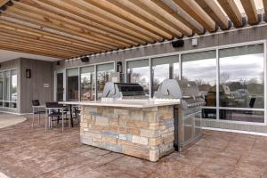 a patio with an outdoor kitchen with a stone fireplace at TownePlace Suites by Marriott Monroe in Monroe