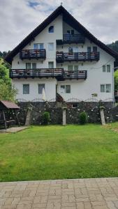 a large white house with a stone fence in front of it at Pensiunea Paula in Moieciu de Sus