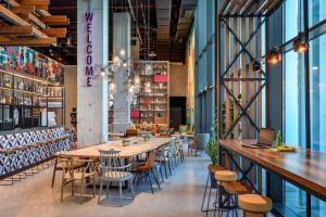 a restaurant with a long table and chairs at Moxy Lisboa Oriente in Lisbon