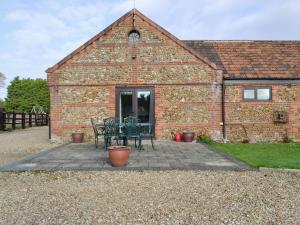 a brick building with a table and chairs in front of it at Baileys Barn - Ukc3738 in Bawdeswell