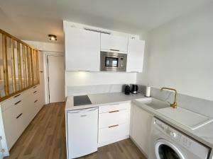 a kitchen with white cabinets and a washer and dryer at 06AI - Beau studio rénové - vue mer et piscine in Vallauris