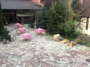 un groupe de tables et de chaises roses sur une terrasse en pierre dans l'établissement Muzey-sadyba Grazhda, à Bukovel