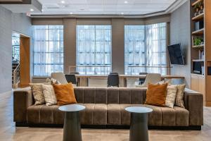 a living room with a couch and tables and windows at Sheraton Suites Wilmington Downtown in Wilmington