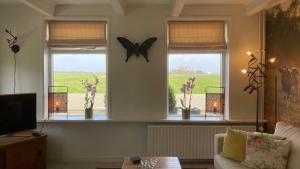 una sala de estar con 2 ventanas con mariposas. en Appartement Greidesicht Kollumerpomp en Kollumerpomp