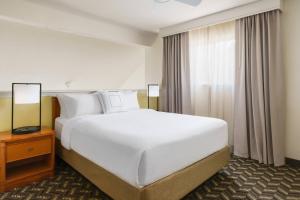 a large white bed in a hotel room with a window at Residence Inn Hartford Windsor in Windsor