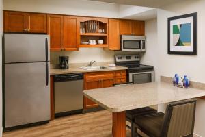 una cocina con electrodomésticos de acero inoxidable y armarios de madera en Residence Inn Hartford Windsor en Windsor