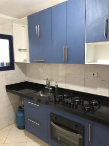 una cucina con armadi blu e lavandino di María Cristina ,ar,Wi-Fi e tv a cabo a Praia Grande
