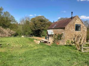 una vieja casa de piedra en un campo con una valla en Whichford Mill Barn- Soulful retreat. en Shipston on Stour