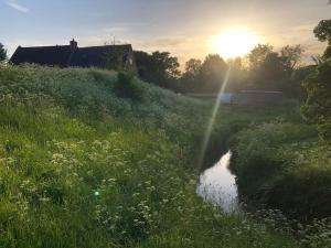 ein Grasfeld mit Sonnenuntergang im Hintergrund in der Unterkunft Whichford Mill Barn- Soulful retreat. in Shipston on Stour