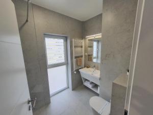 a bathroom with a toilet and a sink and a window at MIANELLY Apartments Mamaia Nord in Mamaia Nord +145 photos