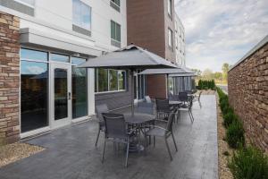 un patio con mesas, sillas y una sombrilla en Fairfield Inn & Suites by Marriott Kenosha Pleasant Prairie en Pleasant Prairie