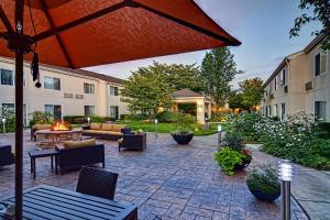 an outdoor patio with an umbrella and chairs and tables at Courtyard by Marriott Eugene Springfield in Springfield