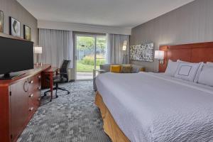 a hotel room with a bed and a desk and a television at Courtyard by Marriott Eugene Springfield in Springfield
