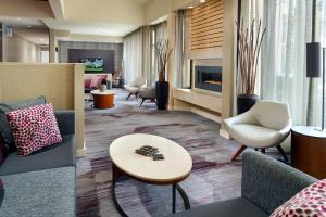 a lobby with couches and chairs and a fireplace at Courtyard by Marriott Raleigh Midtown in Raleigh