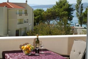 einen Tisch mit einer Flasche Wein und einer Schale Obst in der Unterkunft Apartmani Villa Dijana-Promajna in Promajna