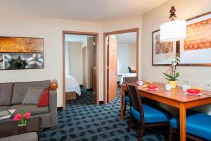 Habitación de hotel con mesa y sala de estar. en TownePlace Suites by Marriott Indianapolis - Keystone, en Indianápolis