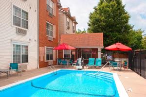 a swimming pool with chairs and umbrellas next to a building at TownePlace Suites by Marriott Indianapolis - Keystone in Indianapolis