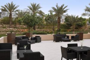 d'une terrasse avec des tables, des chaises et des palmiers. dans l'établissement Courtyard Riyadh by Marriott Diplomatic Quarter, à Riyad