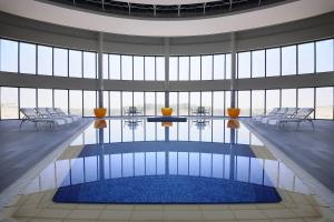 - une grande piscine avec des chaises dans une grande pièce dotée de fenêtres dans l'établissement Courtyard Riyadh by Marriott Diplomatic Quarter, à Riyad