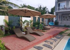a patio with two chairs and an umbrella next to a pool at Yas Villa - Stay, Play & Enjoy. Bagac, Bataan in Bagac