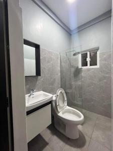 a white bathroom with a toilet and a sink at Yas Villa - Stay, Play & Enjoy. Bagac, Bataan in Bagac