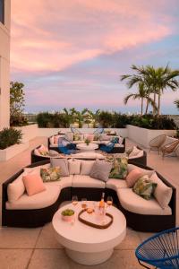 un patio con sofás, mesas y palmeras en The Dalmar, Fort Lauderdale, a Tribute Portfolio Hotel en Fort Lauderdale