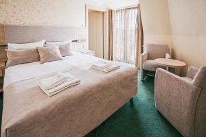 ein Hotelzimmer mit einem großen Bett und einem Stuhl in der Unterkunft Villa Cannes in Jastarnia