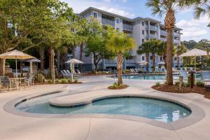 a pool at a resort with palm trees and a building at Marriott's SurfWatch in Hilton Head Island