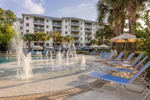a fountain in front of a hotel with lounge chairs and a building at Marriott's SurfWatch in Hilton Head Island