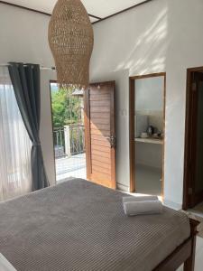ein Schlafzimmer mit einem Bett und eine Tür mit einem Spiegel in der Unterkunft Villa iris Homestay in Uluwatu