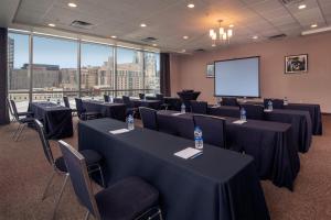 una sala de conferencias con mesas, sillas y una pantalla en Four Points Philadelphia City Center, en Filadelfia