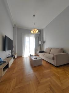 uma sala de estar com um sofá e um piso de madeira em Hermes - Acropolis Residence Apartment em Atenas