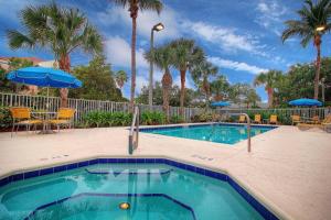 a swimming pool with chairs and umbrellas in a resort at Fairfield Inn & Suites By Marriott Jupiter in Jupiter