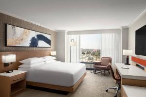 ein Hotelzimmer mit einem weißen Bett, einem Schreibtisch und einem Schreibtisch in der Unterkunft Delta Hotels by Marriott Anaheim Garden Grove in Anaheim