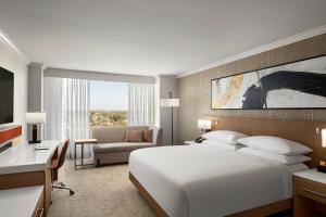 a bedroom with a large white bed and a desk and a room at Delta Hotels by Marriott Anaheim Garden Grove in Anaheim