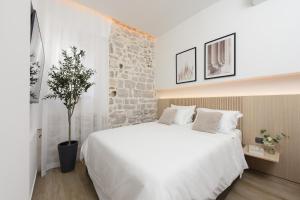 a bedroom with a large white bed and a stone wall at NEW!Beautiful modern bedrooms and apt Old town Zadar- Great location in Zadar