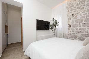 a bedroom with a white bed and a stone wall at NEW!Beautiful modern bedrooms and apt Old town Zadar- Great location in Zadar