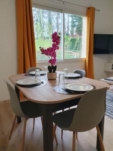 un tavolo in legno con sedie e un tavolo con fiori di Appartement neuf, très lumineux a Hautot-sur-Mer