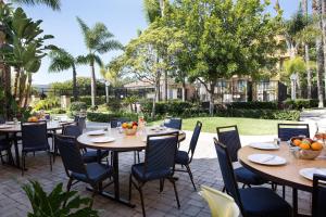 un patio al aire libre con mesas, sillas y árboles en Courtyard Costa Mesa South Coast Metro en Santa Ana