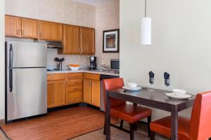 a kitchen with a refrigerator and a table with chairs at Residence Inn by Marriott Bloomington by Mall of America in Bloomington