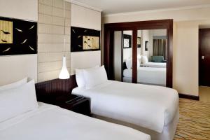 a hotel room with two beds and a mirror at Four Points By Sheraton Riyadh Khaldia in Riyadh