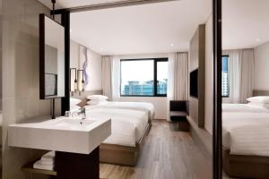 釜山にあるFairfield by Marriott Busanのベッド2台、シンク、鏡が備わるホテルルームです。