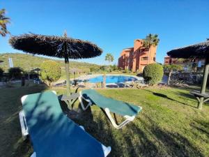 2 leżaki i parasol przy basenie w obiekcie Apartamento de tres dormitorios muy espacioso con jardines y piscinas w mieście Estepona