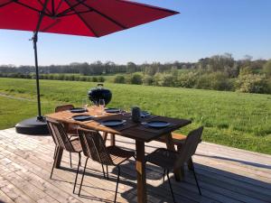 drewniany stół z krzesłami i parasol na tarasie w obiekcie Maison de charme vue d'exception w mieście Étreham